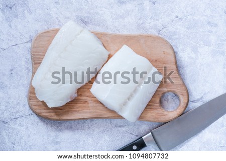 Raw cod fillets on wooden board - top view