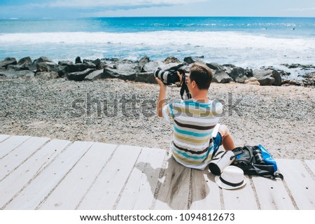 handsome young guy the photographer working with a laptop on the beach
