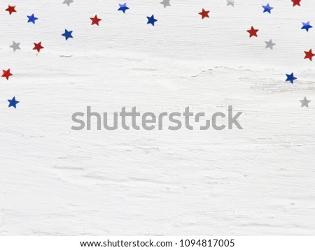 Glittering confetti stars on old grunge wooden background. 4th July, Independence day, card, invitation in usa flag colors. Top view, flat lay, empty space.