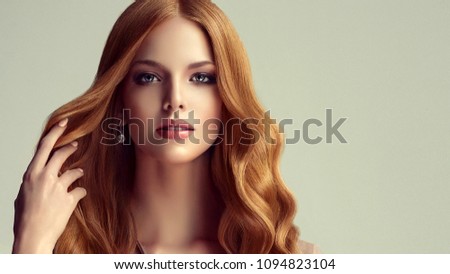 Red head  girl with long  and   shiny curly    hair .  Beautiful  model woman with  wavy hairstyle . 
