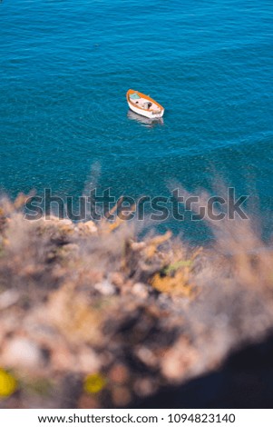 A lonesome boat moored in the bay. Deep blue see and a  small wooden boat.