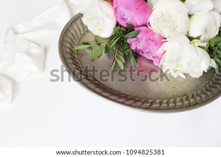 Styled stock photo. Feminine wedding or birthday table composition with floral bouquet. White and pink peonies flowers on old vintage silver tray and silk ribbon. White background. Picture for blog.