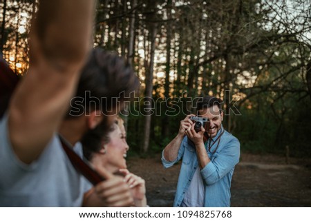Young man taking a photo of his friends in the woods