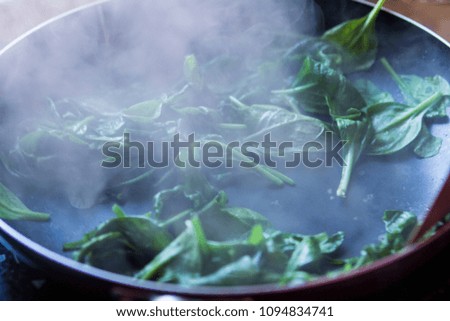 spinach in a frying pan in the smoke closeup