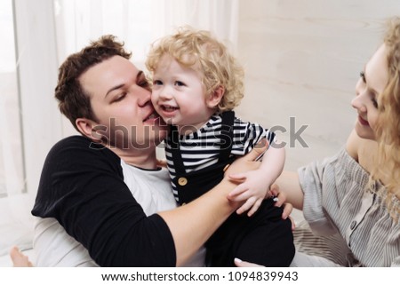 friendly happy family spends time together, parents play with their little curly-haired son