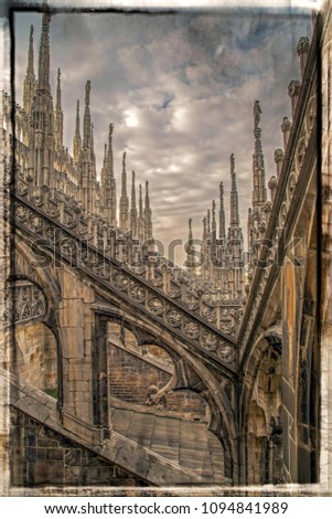 Old photo with architectonic details from roof of the famous Milan Cathedral, Lombardy, Italy. Famous spire. Border filter applied and vintage processing.