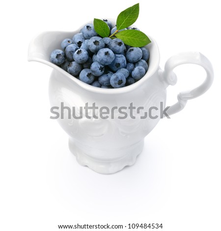 White jug full of blueberries isolated over white