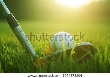 Blurred golf club and golf ball close up in grass field with sunset. Golf ball close up in golf coures at Thailand Royalty-Free Stock Photo #1094873204