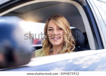 Attractive young woman driving a car. Beautiful blonde in the car salon.