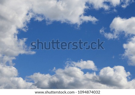 The blue sky with a lot of white clouds of different sizes, forming a frame around the cloudless area