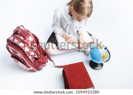 little cute girl school girl sitting with books and a globe,reading a book, on a white background, advertisement,