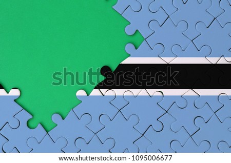 Botswana flag  is depicted on a completed jigsaw puzzle with free green copy space on the left side.