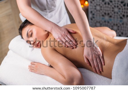 young beautiful woman with closed eyes is receiving massage for full body. closeup cropped photo