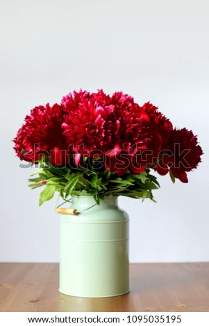 Maroon peonies in a vase on the table. Copy Space