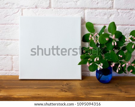 Mock up poster in modern interior with pink flowers. White empty canvas.