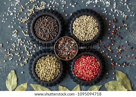 Four variations of peppercorns on dark stone table. Spice  background.  set of condiments. Ingredients for cooking. Food background  Top view,  copy space