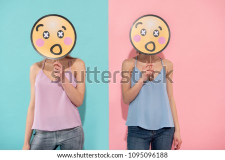 Waist up of two shocked female people posing in blue and pink t shirts of the same style