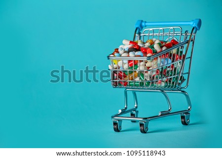 Shopping cart filled with pills. Blue background. Concept: full set of medicines in the store. Copy space for text Royalty-Free Stock Photo #1095118943