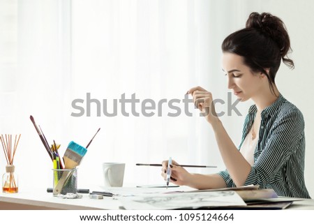 Girl painter working in the office. mascara brush. artist`s workplace. White background