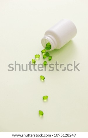 Green capsules in a bottle isolated on white background