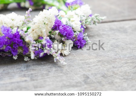 Purple and white flowers placed on an old wooden table.