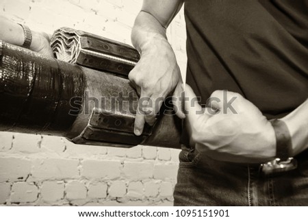 In the picture, the pipe and hands of the worker. The manager demonstrates the new pipeline protection against corrosion. Black and white image. Horizontal frame. Photographed in Ukraine, Kiev