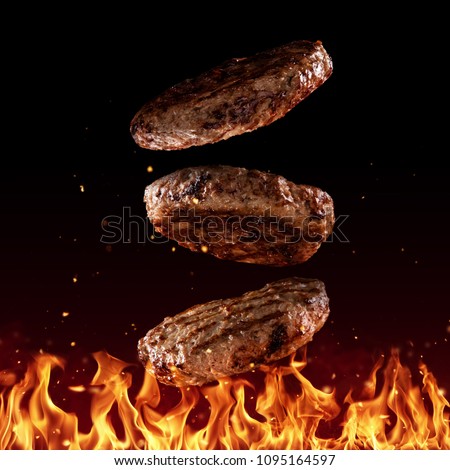 Flying beef minced hamburger pieces above grill flames, isolated on black background. Concept of flying food, very high resolution image