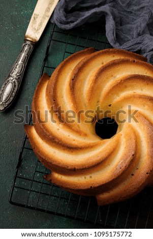 Bundt cake with sugar glaze and coconut on dark green old concrete background. Selective focus. Top view with copy space.