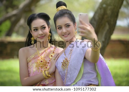 Two friends taking selfie together with Thai dress. Two beautiful Thai woman taking selfie together with cute posture before posing to social media. Party and online presence concept.