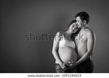 Husband and pregnant wife on gray background, happy couple 