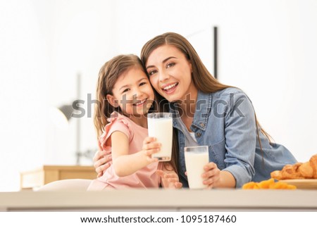Mother and daughter having breakfast with milk at table Royalty-Free Stock Photo #1095187460