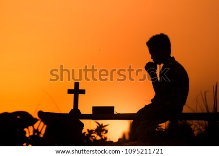 Boy praying to god with light sunset background, christian concept