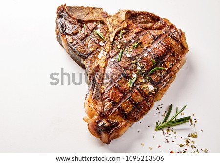 A succulent, grilled t-bone steak and herb garnish with a white background and copy space. Royalty-Free Stock Photo #1095213506