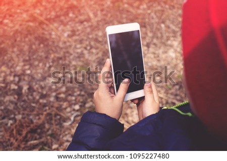 Little boy using smart phone outdoors. Walking child holding a smartphone in his hand