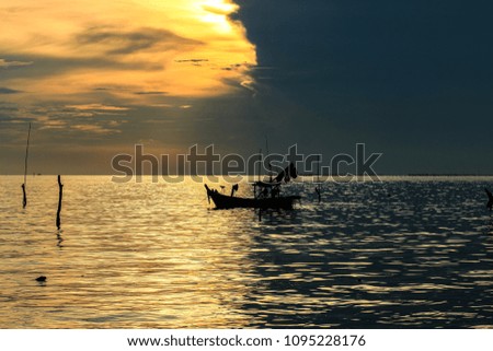 silhouette of fishing boat in sea 2 colors from the shadow of evening clouds.