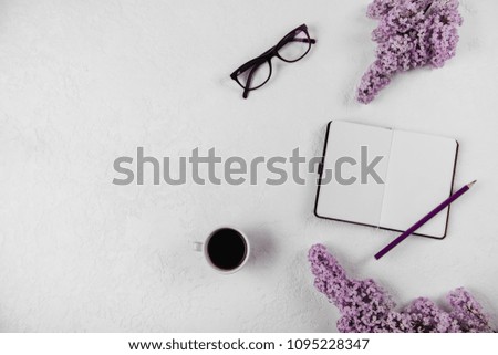 Coffee, macaron, clean notebook, eyeglasses and flower on white table from above. Female working desk. Flat lay style.