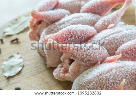 Raw frozen quails, mustard, herbs and spices for marinating on the wooden table. Royalty-Free Stock Photo #1095232802