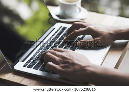hand typing keyboard on wooden table at coffee shop