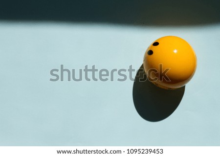 Yellow smiley face circle ball on a blue background, top view. shadow from the sun. Happy work day concept.