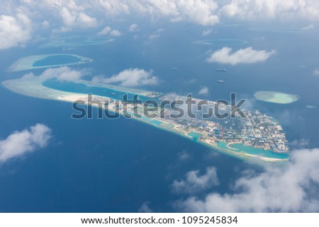 Maldives aerial view. Blue sea and coral reef and blue sky with fluffy clouds. Maldives island birds eye view