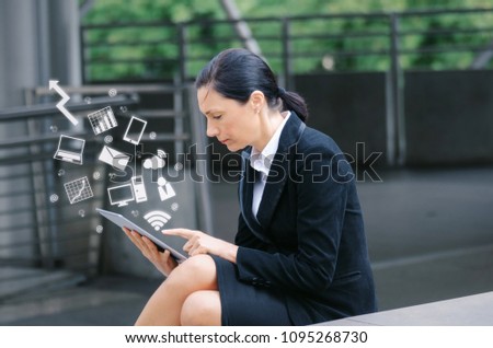 caucasian business woman wearing modern black suit reading information about finance news with mobile tablet in city and graphic icon diagram, technology, internet, investment and stock market concept
