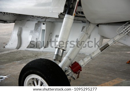 A close-up shot that show a mechanic of an airplane wheel, suspension and hydraulic tubes connected on the wheel's support arms