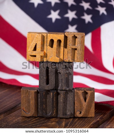 "4th of July" sign using wooden letter blocks with the United States flag in background-American holiday concept