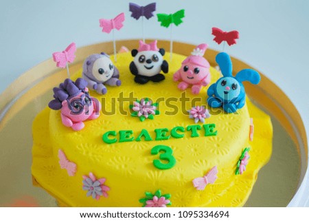 Colorful birthday cake decorated with little cartoon characters on the top.