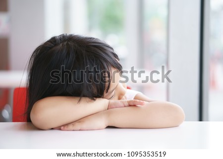 Asian children cute or kid girl sleep or asleep for relax on white table in classroom at school because sleepy or lonely and waiting father and mother with bored at home
