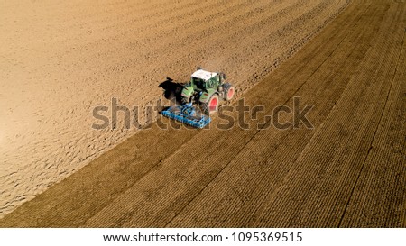 Aerial photo of a tractor ploughing a field in the french countryside