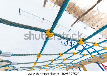 Multicolored children's playground in the courtyard in the winter. wire rope