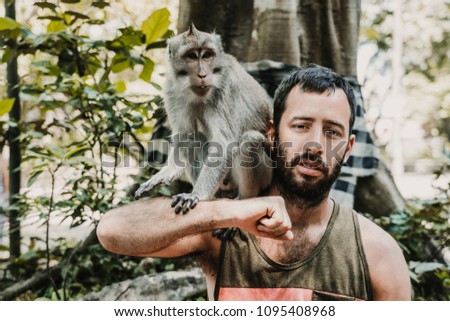 
Young handsome man taking himself some pictures with a cute monkey in the monckey forest in Ubud, Bali. Lifestyle. Travel photography