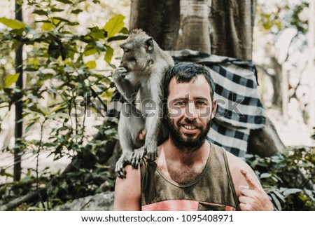 
Young handsome man taking himself some pictures with a cute monkey in the monckey forest in Ubud, Bali. Lifestyle. Travel photography