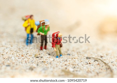 Miniature people: travelers with backpack walking on the beach. Image use for travel, vacation concept.